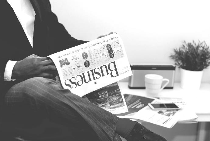 person sitting near table holding newspaper